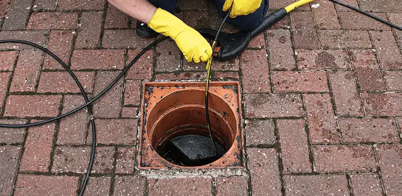 Drain cleaning technician using a drain snake to clear a clogged drain in Ogden, UT