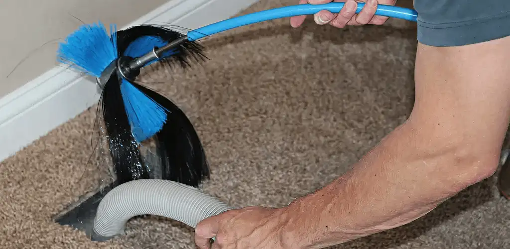 Dryer vent cleaning technician brushing lint from a vent line in Ogden, UT