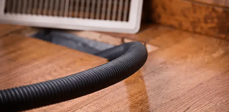 Air duct cleaning hose inserted into a floor vent for ductwork cleaning in Ogden, UT