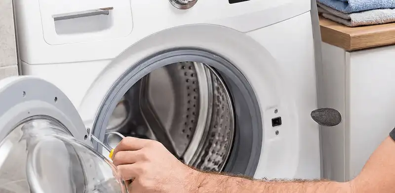 Handyman repairing a front-load washing machine and inspecting the drum in Ogden, UT