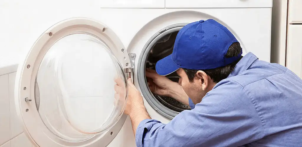 Washing machine repair handyman inspecting a front-load washer drum in Ogden, UT