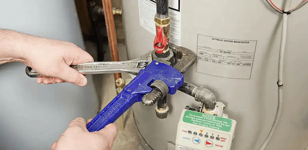 Water heater repair technician tightening the shutoff valve and supply line in Ogden, UT